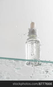 Glass tube of cosmetic product with serum on a glass shelf and water drops on a white background, bottom view. Skin care concept. Glass tube of cosmetic