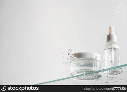 Glass tubes of cosmetic product with serum and cream on a glass shelf and water drops on a white background, bottom view. Skin care concept. Glass tubes of cosmetic
