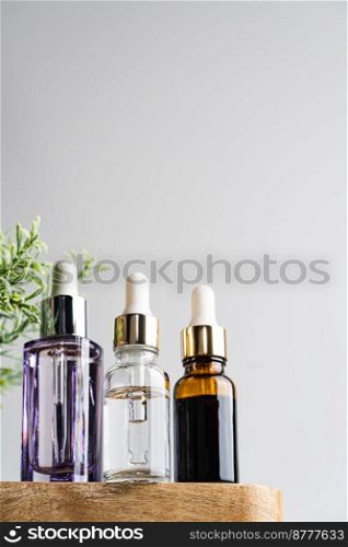 Glass tubes of cosmetic product with serum on wooden shelf on a white background, bottom view. Skin care concept. Glass tubes of cosmetic