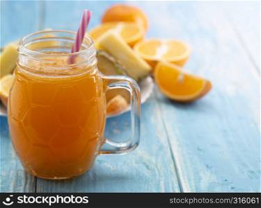 glass vessel with the juice of orange with a straw on a blue table