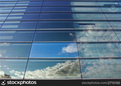 Glass wall of an office building, reflections of clouds. One square is different in color.