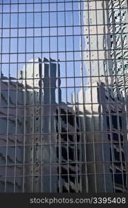 Glass wall with the reflection of blue sky and buildings