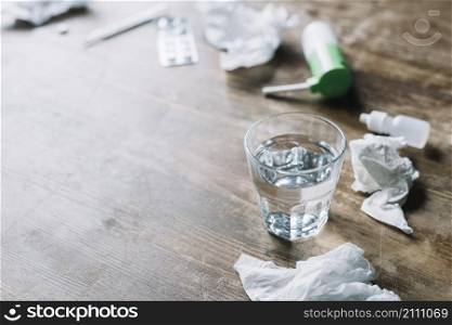 glass water crumpled tissue paper medicines wooden backdrop