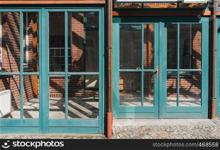 Glass windows and doors with turquoise frames at red bricked european facade