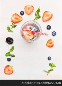 Glass with berries lemonade and ingredients on white wooden background, top view. Detox drink, diet and health food concept