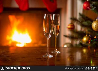Glass with champagne on table in front of burning fireplace