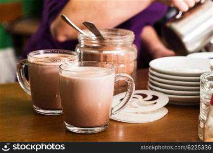 Glass with cocoa with milk on the table in cafe. Cocoa drink cooking