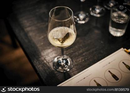 Glass with cold white wine on wooden table at restaurant. 