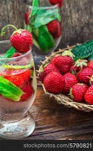 glass with drink of strawberries and mint on the background of the basket full berries.