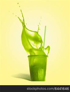 Glass with drinking straw and green splash summer beverage: smoothie or juice on yellow background, front view