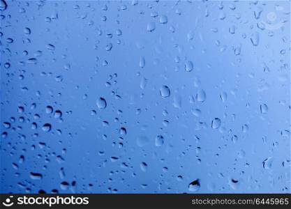 Glass with drops of rain water close up with blue color