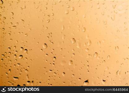 Glass with drops of rain water close up with orange color