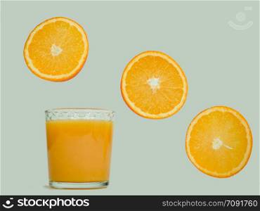 Glass with fresh orange juice, flying orange slices on a white, isolated background. Close-up. Concept of tasty and healthy food. Glass with fresh juice and flying orange slices