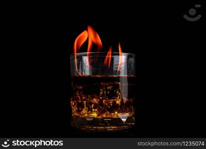 Glass with whiskey of Ice cube and fire flame on black background