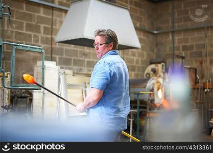 Glassblowers in workshop holding blowpipe