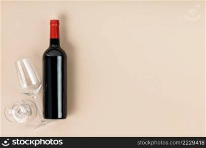 Glasses and bottle with red wine on beige background, flat lay. Space for text