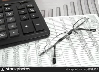 Glasses and calculator on paper table with finance diagram