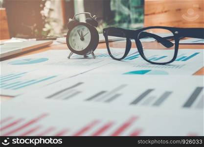 Glasses and clock on the business paper. Report chart