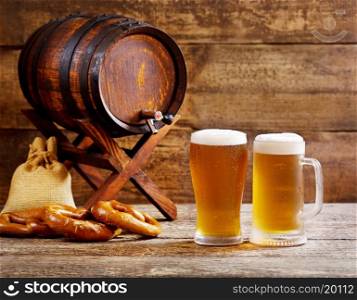 glasses of beer with barrel on wooden background