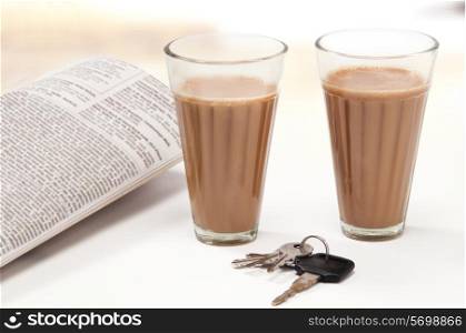 Glasses of chai with car keys and newspaper
