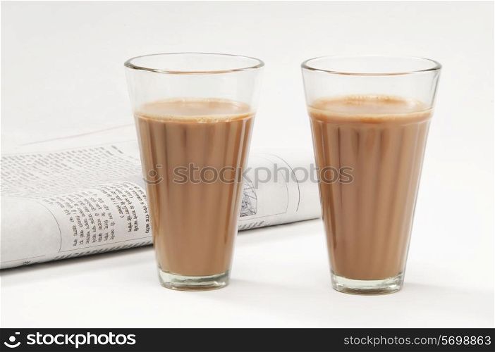 Glasses of chai with newspaper isolated on white background