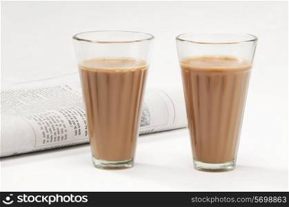 Glasses of chai with newspaper isolated on white background
