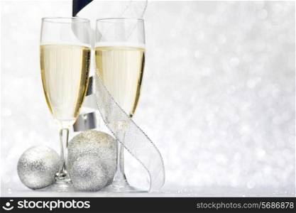 Glasses of champagne and christmas decorative balls on glitter background