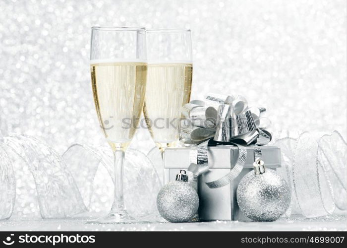 Glasses of champagne and christmas gifts on silver background