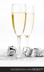 Glasses of champagne and christmas gifts on silver background