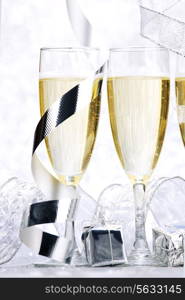 Glasses of champagne and christmas gifts on silver background