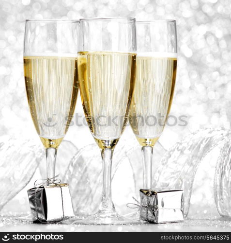 Glasses of champagne and christmas gifts on silver background