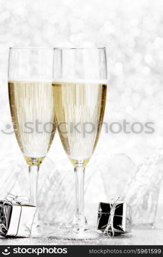 Glasses of champagne and christmas gifts on silver background