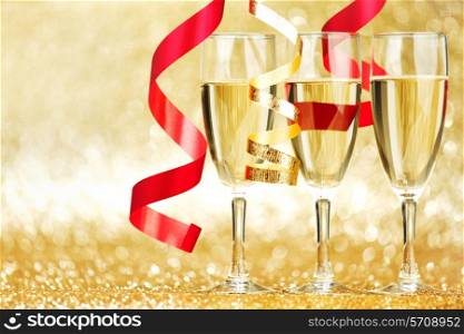 Glasses of champagne and colorful ribbons on glitter background