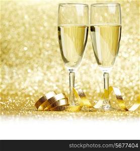 Glasses of champagne and curly decorative ribbon on golden glitters