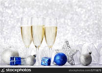 Glasses of champagne and decorative christmas balls on glitter background