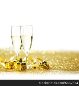 Glasses of champagne and decorative golden gifts isolated on white