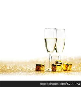 Glasses of champagne and decorative golden gifts isolated on white