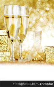 Glasses of champagne and present on golden glitter background