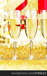 Glasses of champagne and red ribbons on golden background. Champagne and ribbons