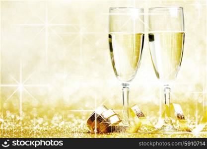 Glasses of champagne and ribbon on golden glitters