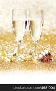 Glasses of champagne and ribbon on golden glitters isolated on white