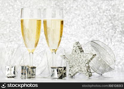 Glasses of champagne and silver gifts on glitter background