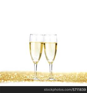 Glasses of champagne on golden glitters isolated on white