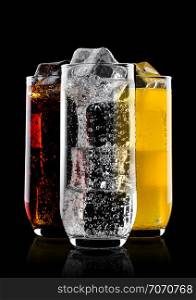 Glasses of cola and orange soda drink and lemonade sparkling water on black background with ice cubes
