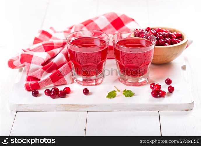 glasses of cranberry juice with fresh berries on wooden table