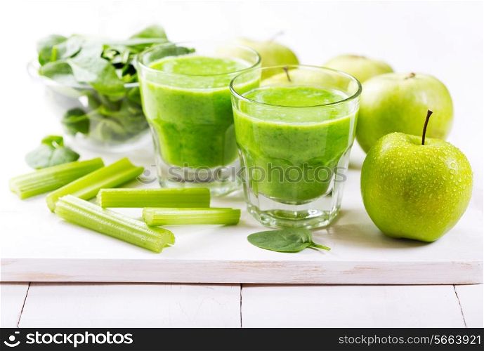 glasses of green juice with apple and spinach on wooden table