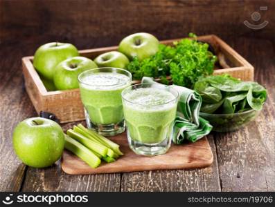 glasses of green juice with apple, celery and spinach on wooden table