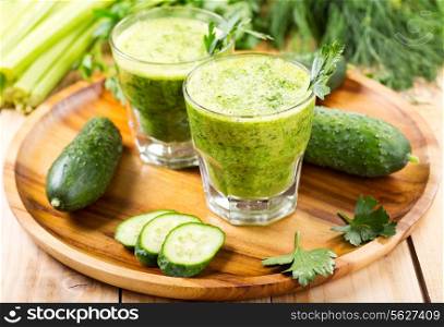 glasses of green vegetable juice on wooden plate