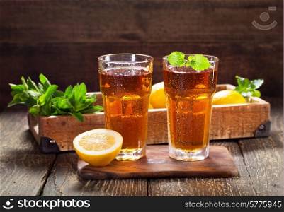 glasses of ice tea with mint and lemon on wooden table