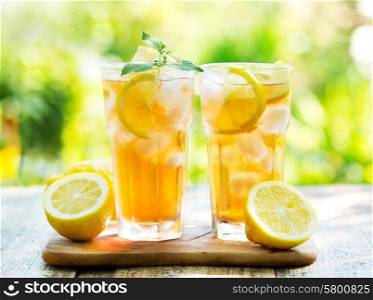 glasses of ice tea with mint and lemon on wooden table